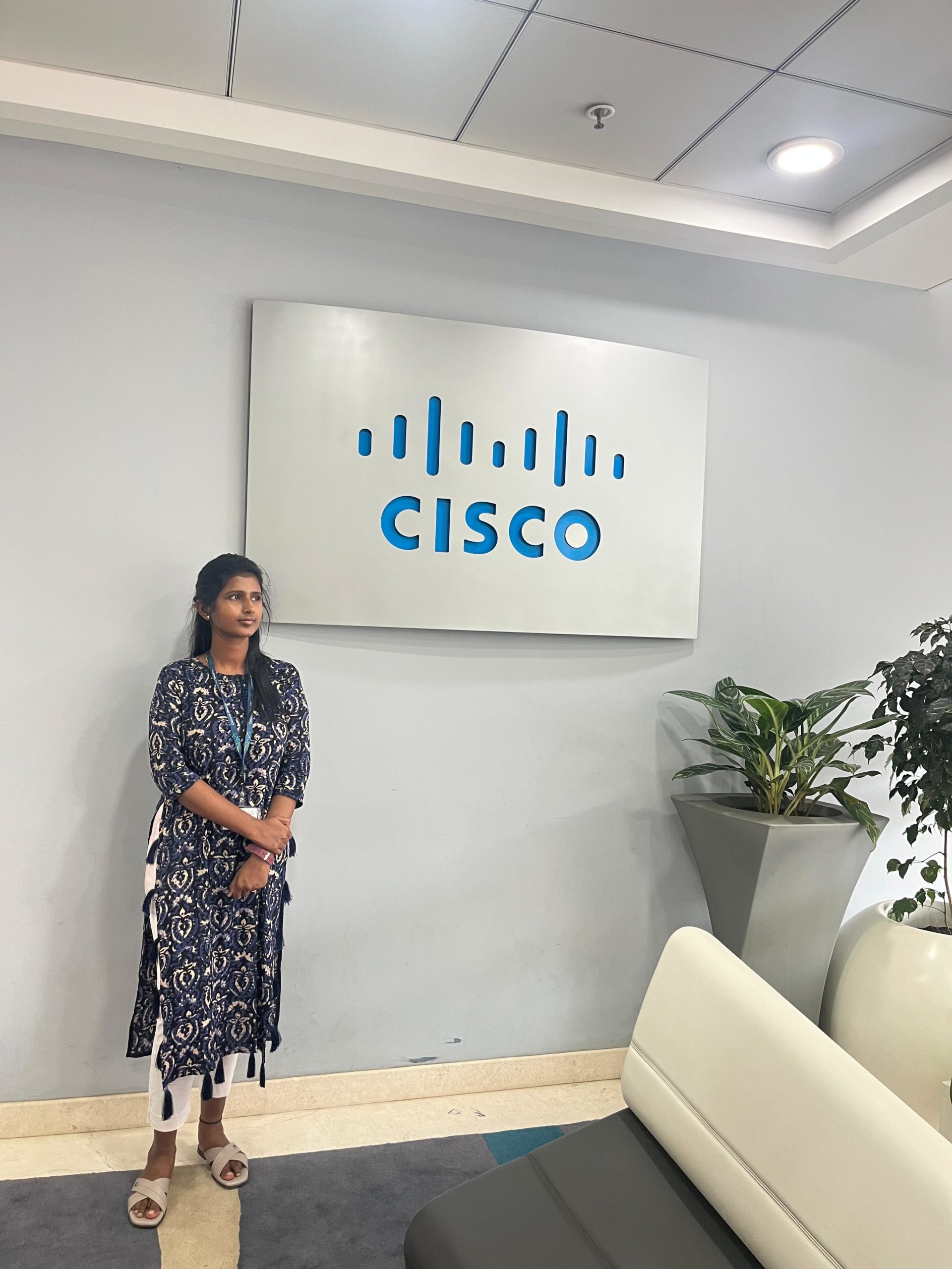 Woman standing on front of large Cisco sign in an office building.