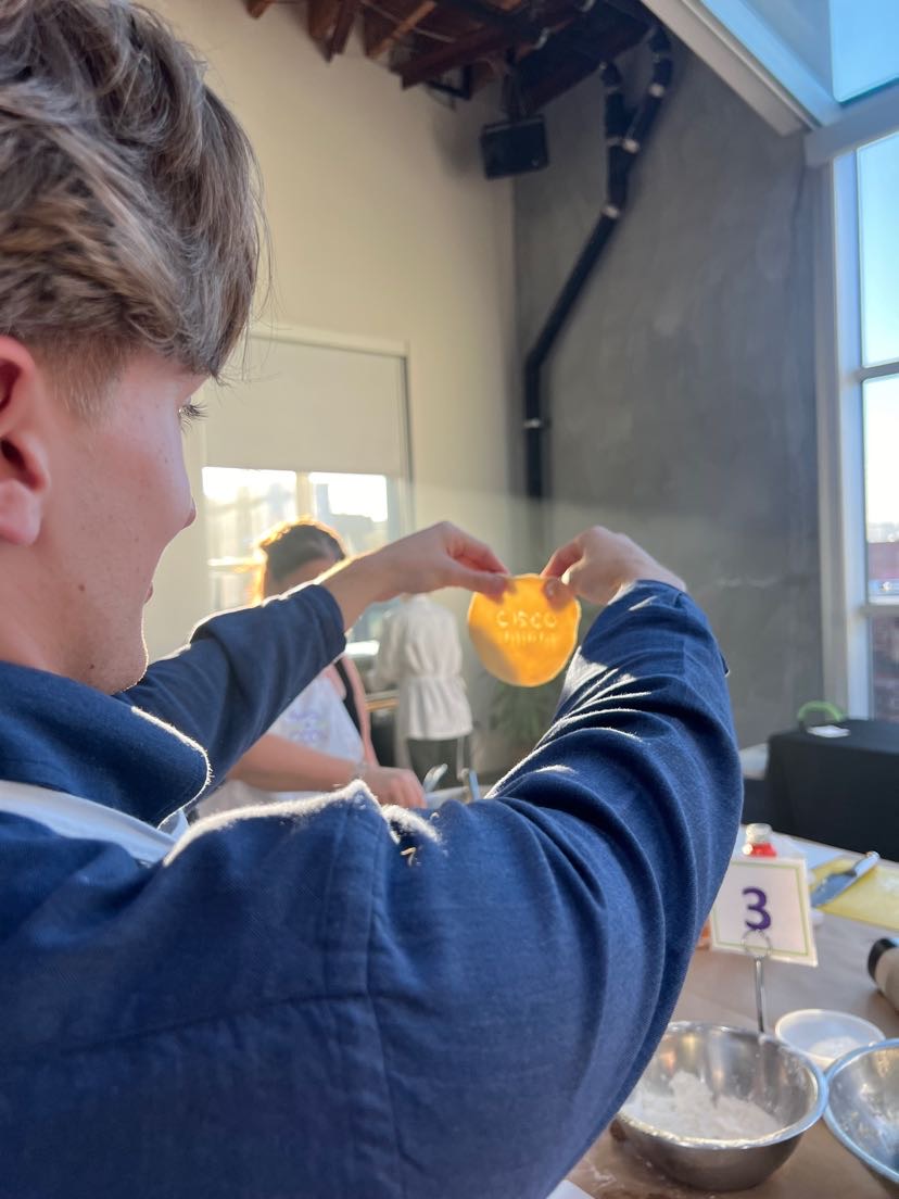 Man holding a circle of cookie dough with Cisco logo on it.