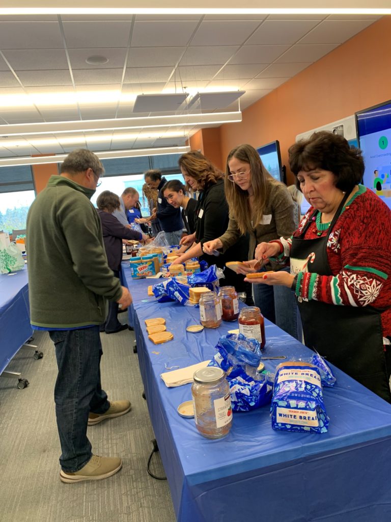Image of an assembly line of volunteers making peanut butter and jelly sandwiches. 