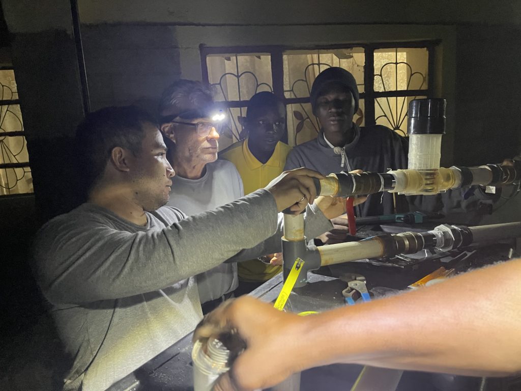 Image of a group of volunteers wearing headlamps working on the water filtration system at an orphanage. 