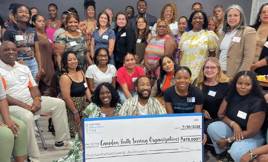Group of people at Camden Dream Center holding a check with $475,000 on it. 