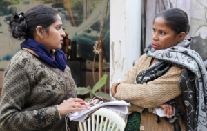 Two women talking together while one on the left takes notes