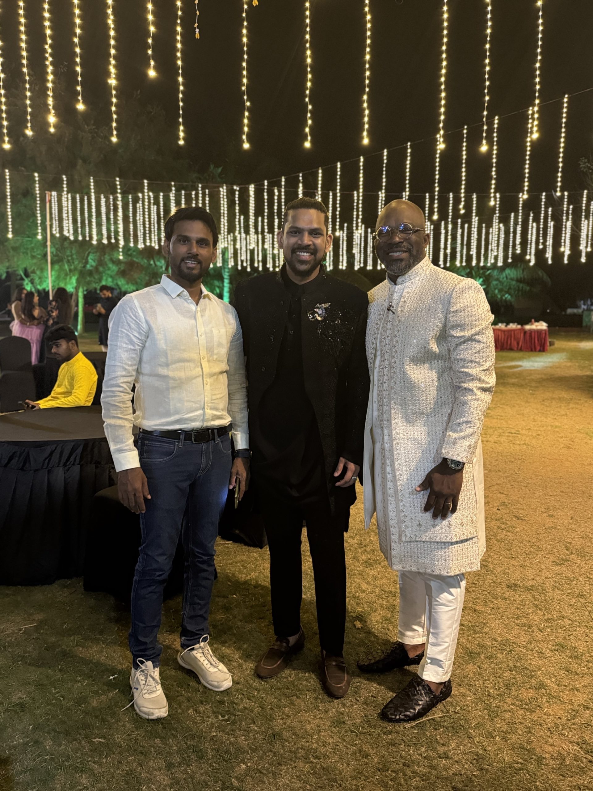 Three men standing next to each other, one wearing a traditional Indian garb.