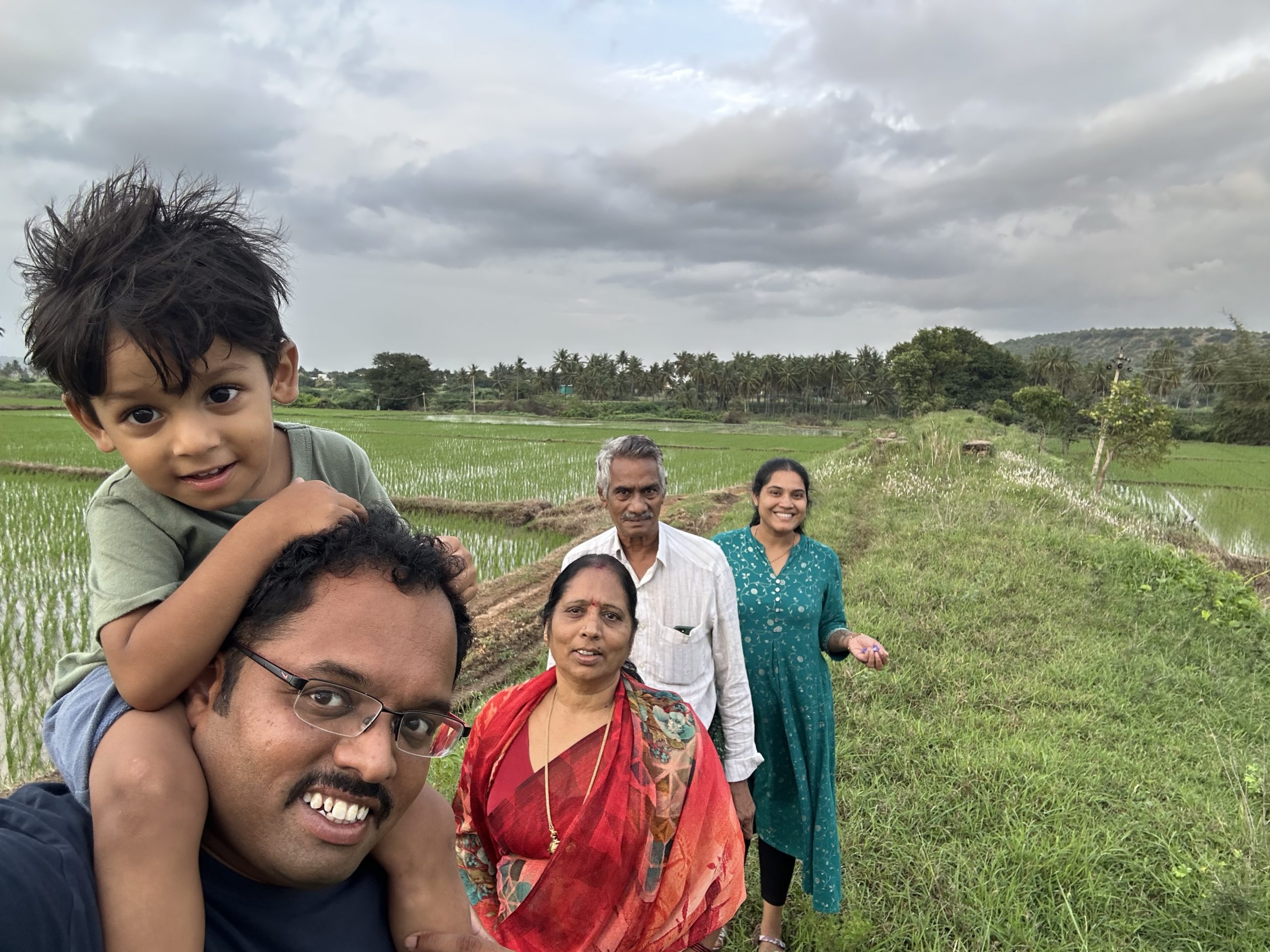A family posing for a photo, with farmland behind them.