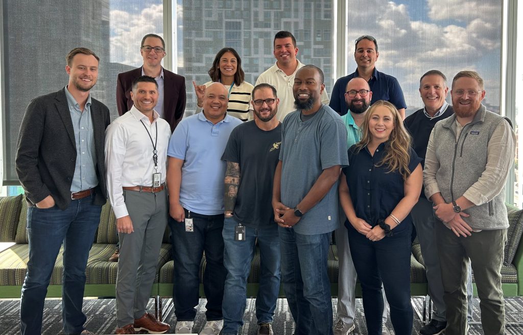 Image of group of people in three rows posing in an office space.