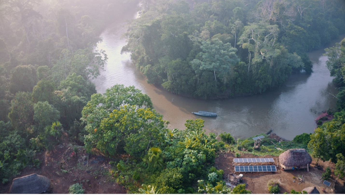 A river with green trees and solar panels