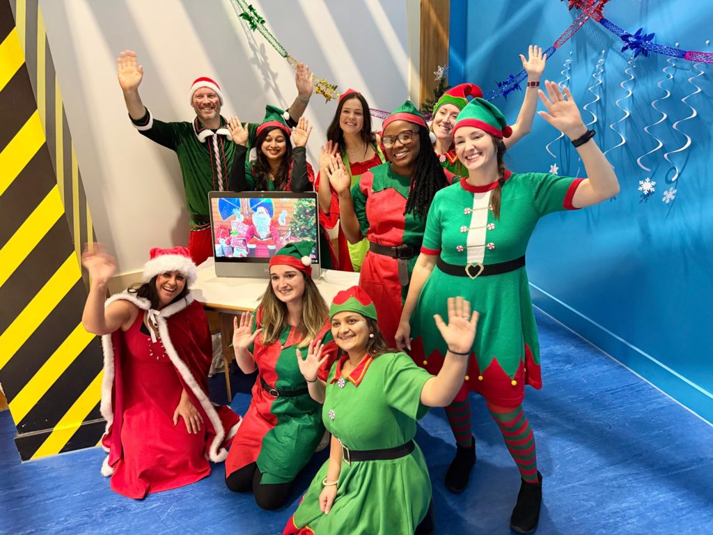 Group of Cisco employees dressed in elf costumes with a Webex monitor in the center. 