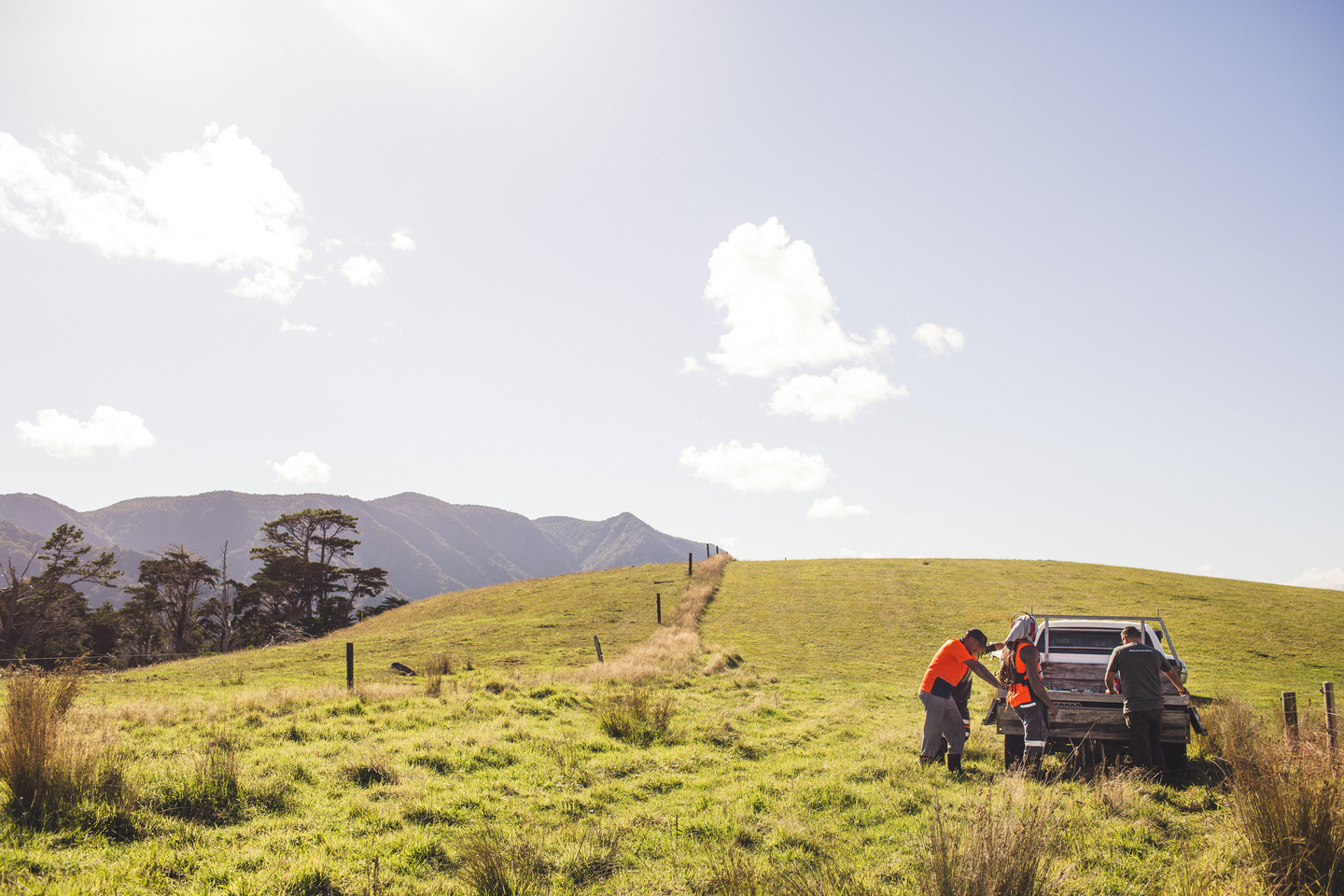 A green landscape with a vehicle and two people.
