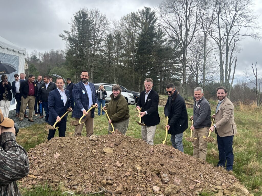 A group of seven men holding shovels in front of a large mound of soil during the groundbreaking for a new housing build in North Carolina.