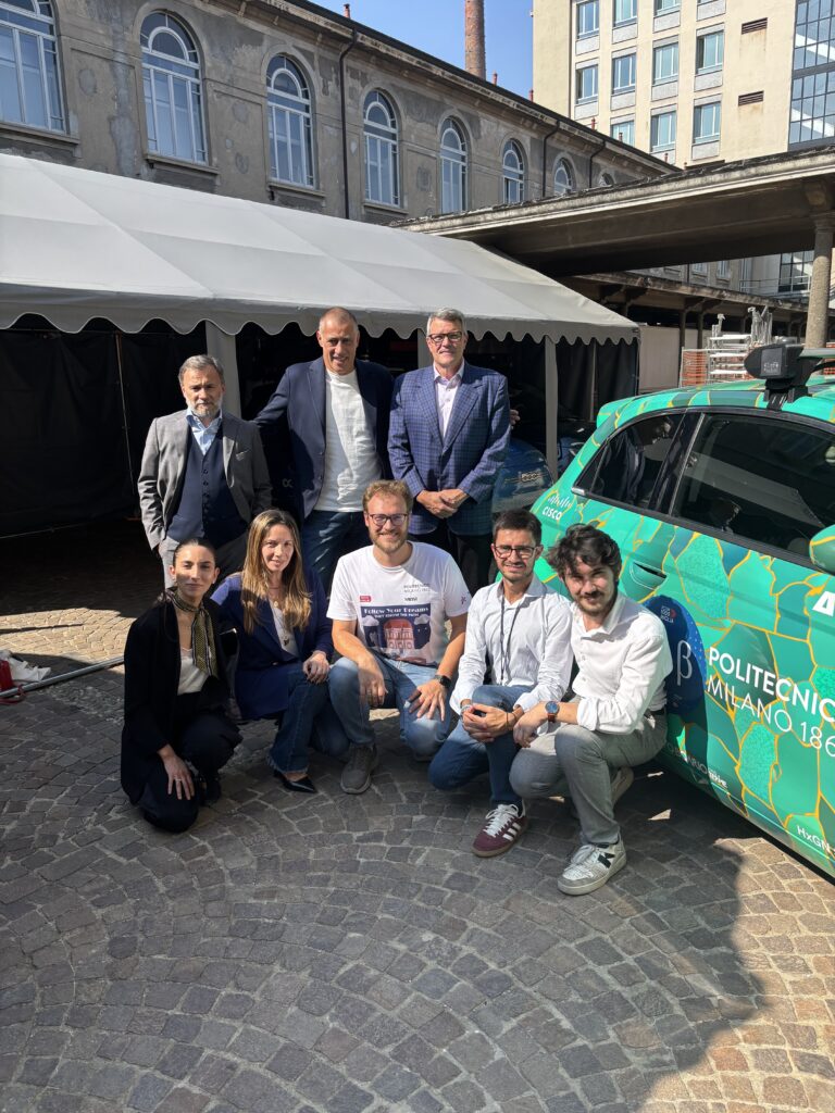 Two rows of people posing next to a Sharing for Caring car.