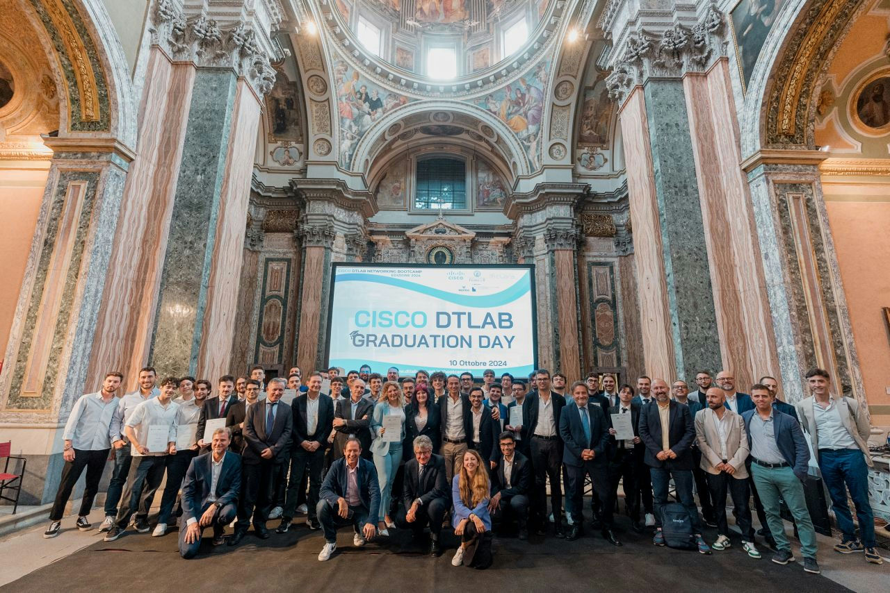 A large group of people in a grant setting standing in front of a screen.