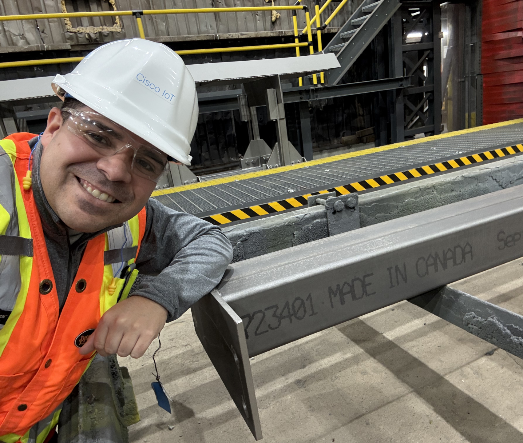 Selfie in safety gear at an industrial facility next to a large steel beam.