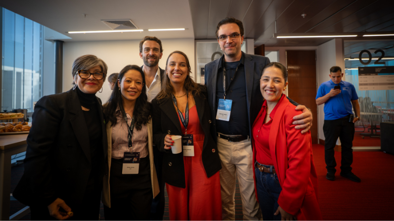 A diverse group of five attendees standing together and smiling during a networking break at the event.