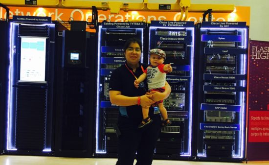 Roxana traveling for work with her baby and posing in front of computer gear.