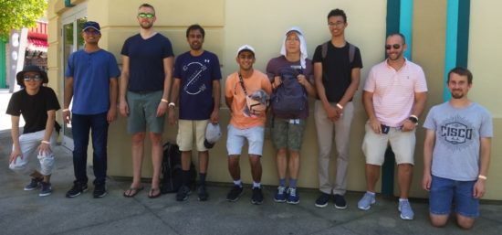 Dhwan standing with coworkers in a line against a wall.