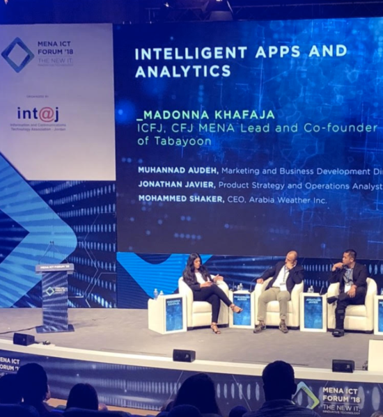 Jonathan sitting on stage with two other speakers giving a talk on Intelligent Apps and Analytics.