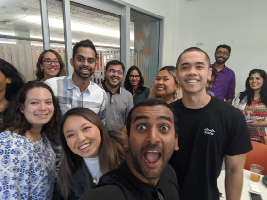 Jonathan in a room at Cisco smiling for the camera with his teammates and peers.